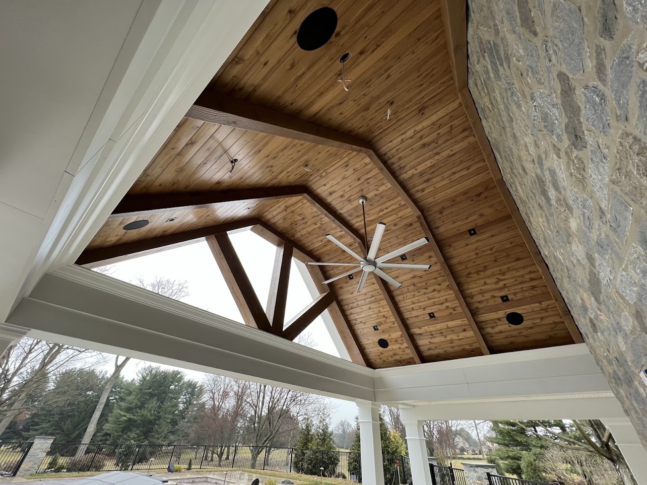 Pool-house wood ceiling with four black recessed speakers installed by Grimwood’s Home Systems