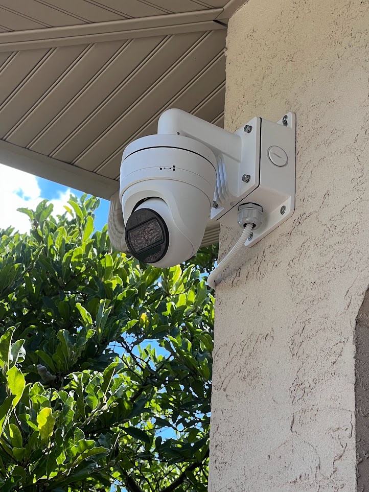 White exterior surveillance camera installed beneath a roof overhang
