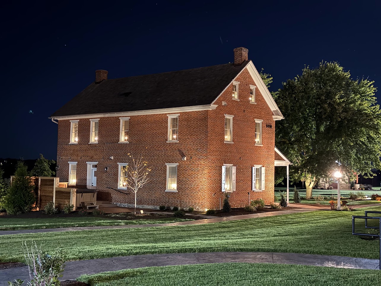 Kissel Valley Farm farmhouse in Lititz, PA, at dusk, with illuminated low-voltage window candles.