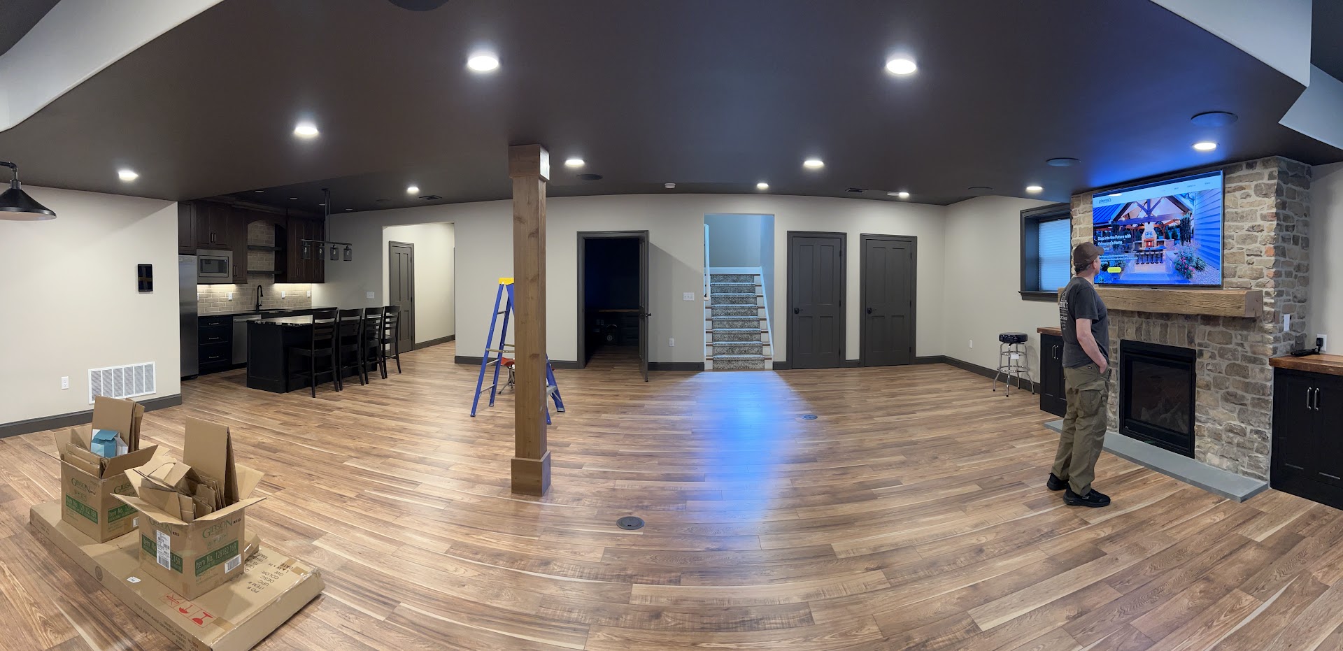 Lancaster home’s lower-level entertainment space with a fireplace-mounted TV and ceiling speakers.