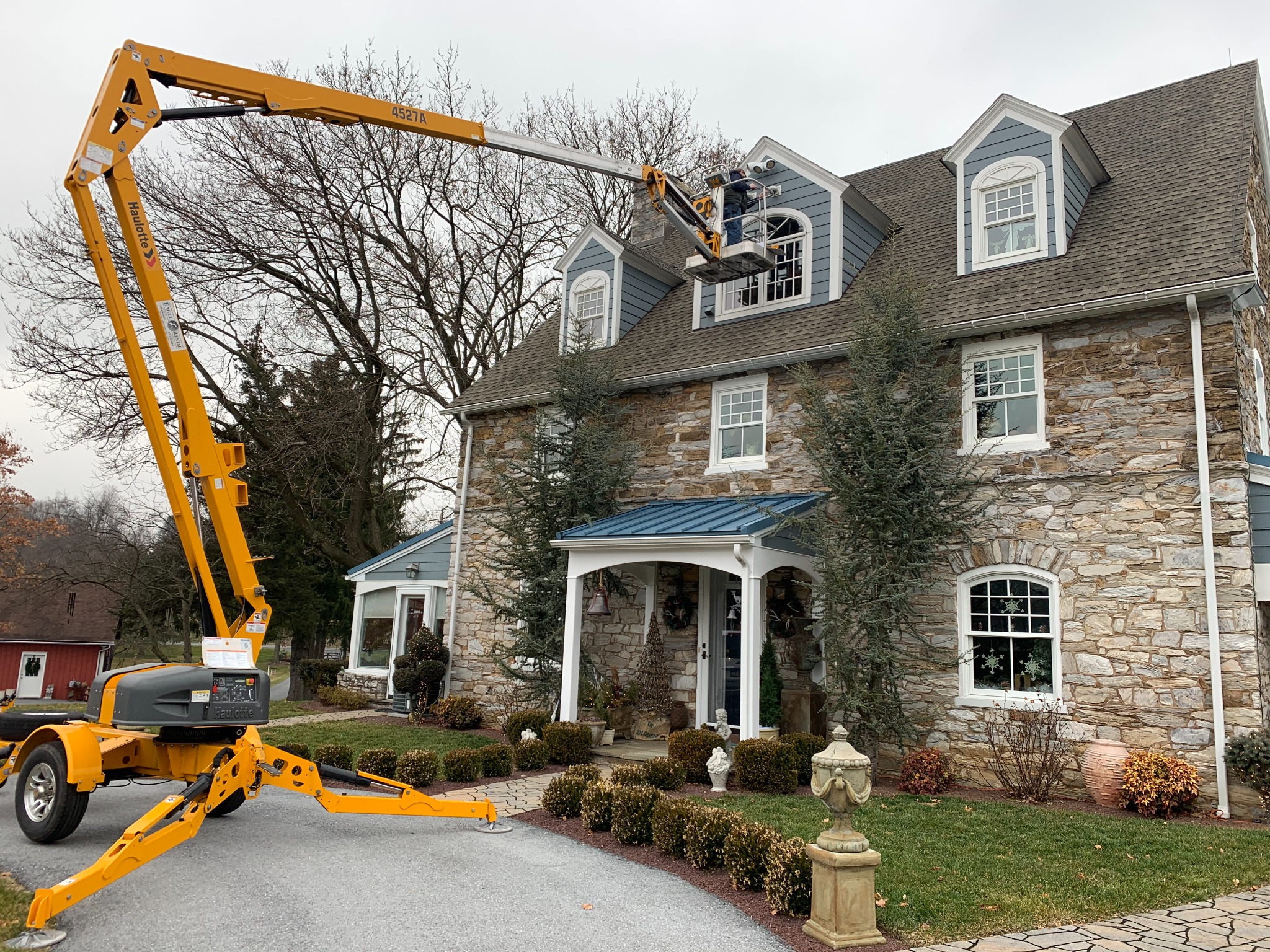 Technician using a lift to replace elevated cameras as part of a residential surveillance system upgrade